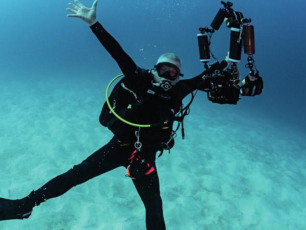 Diver posing with arms outstretched in blue ocean waters