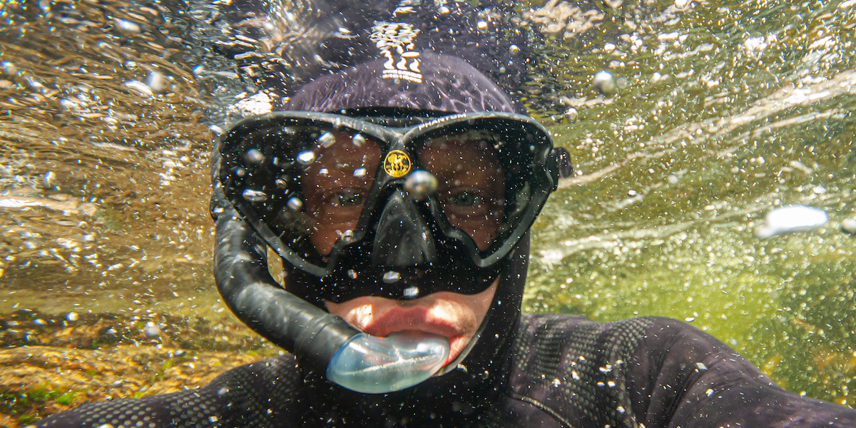 A snorkeller takes a selfie under the surface of the water