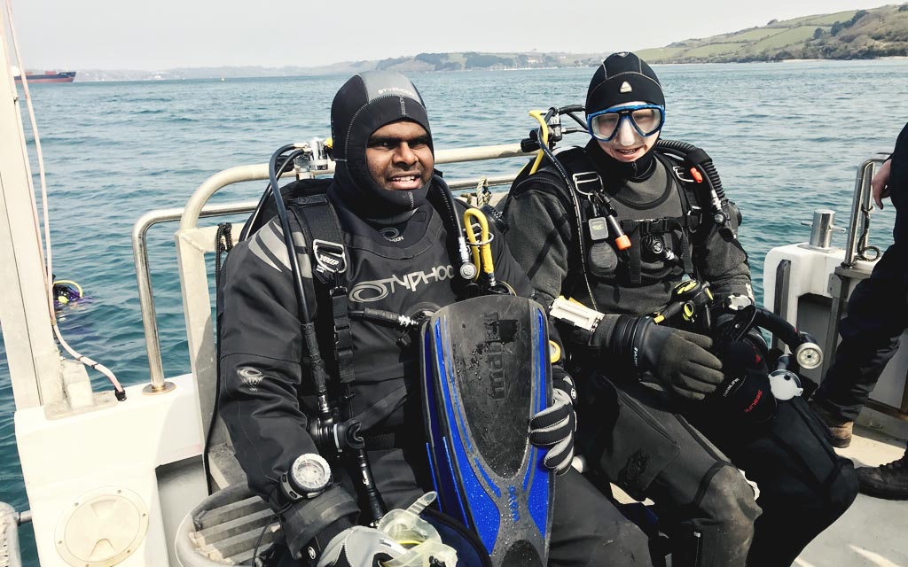 2 divers in full kit looking on a deck ready for a dive