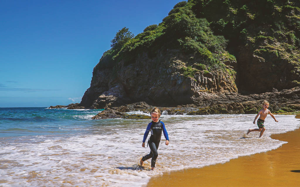 two children running from the waves playfully at the beach at La Geve de Leq