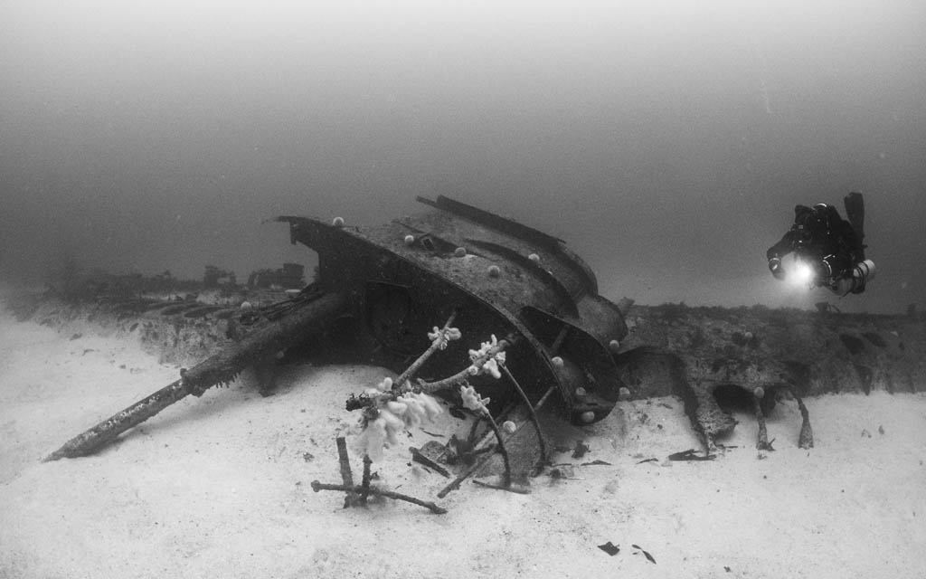 black and white image of diver exploring a metal wreck