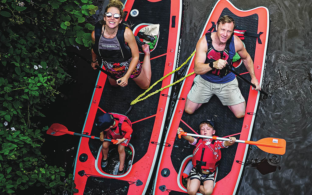 Top down view of two paddleboards with two occupants each looking up at the camera