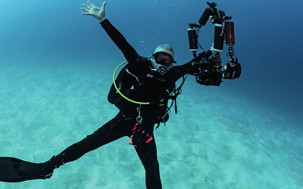 Diver posing with arms outstretched in blue ocean waters