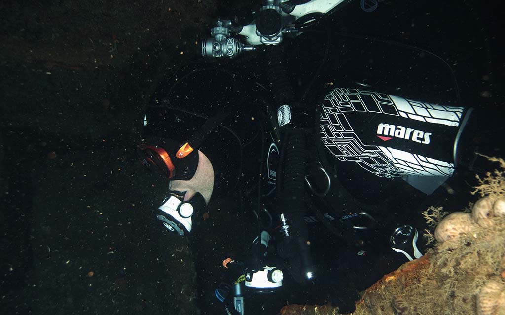 diver penetrating a wreck by a reef