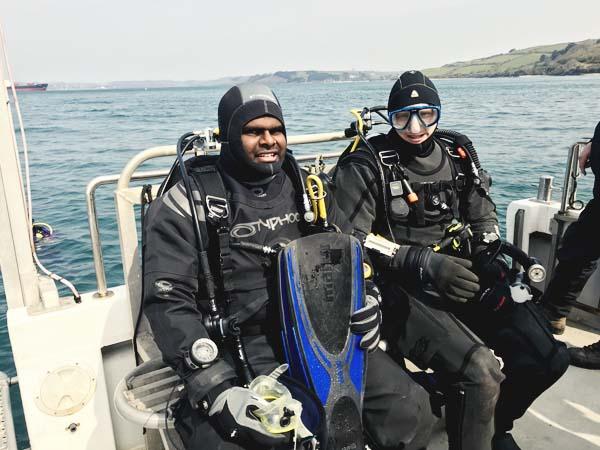 2 divers in full kit looking on a deck ready for a dive