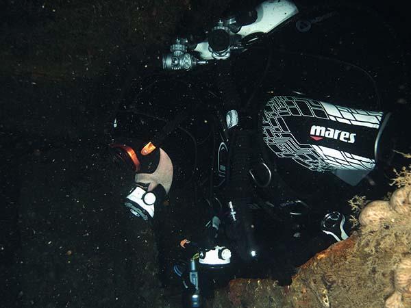diver penetrating a wreck by a reef