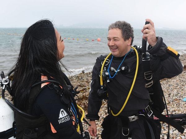 2 divers inspecting breathing equipment at the beach