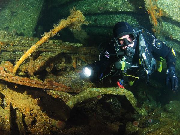 Diver illuminating a wreck with a flashlight