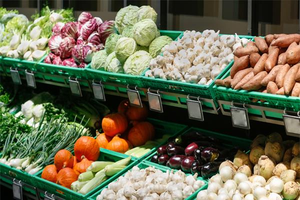 Vegetables in a greengrocer, stacked instead of individually wrapped in plastic. Cabbages, garlic, sweet potato, spring onion, pumpkin, aubergine.