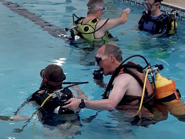 Man helping a young diver on a try dive in a swimming pool