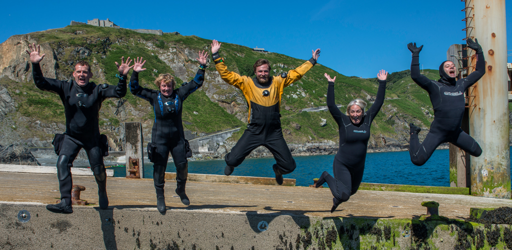 Welcome to the new BSAC website - divers jumping off harbour into water on a sunny day