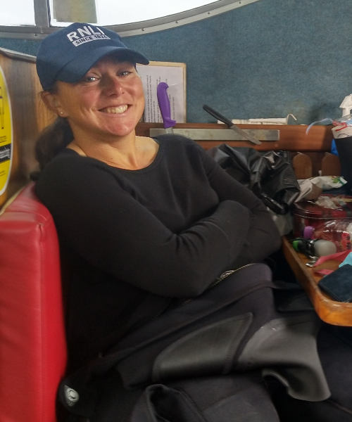 Fran sits in a boat in her drysuit