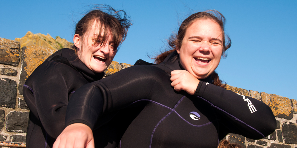 Women getting ready to dive putting on dryuits