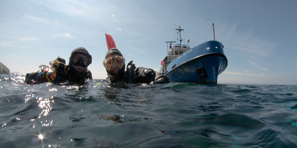 Two divers top side with boat in background