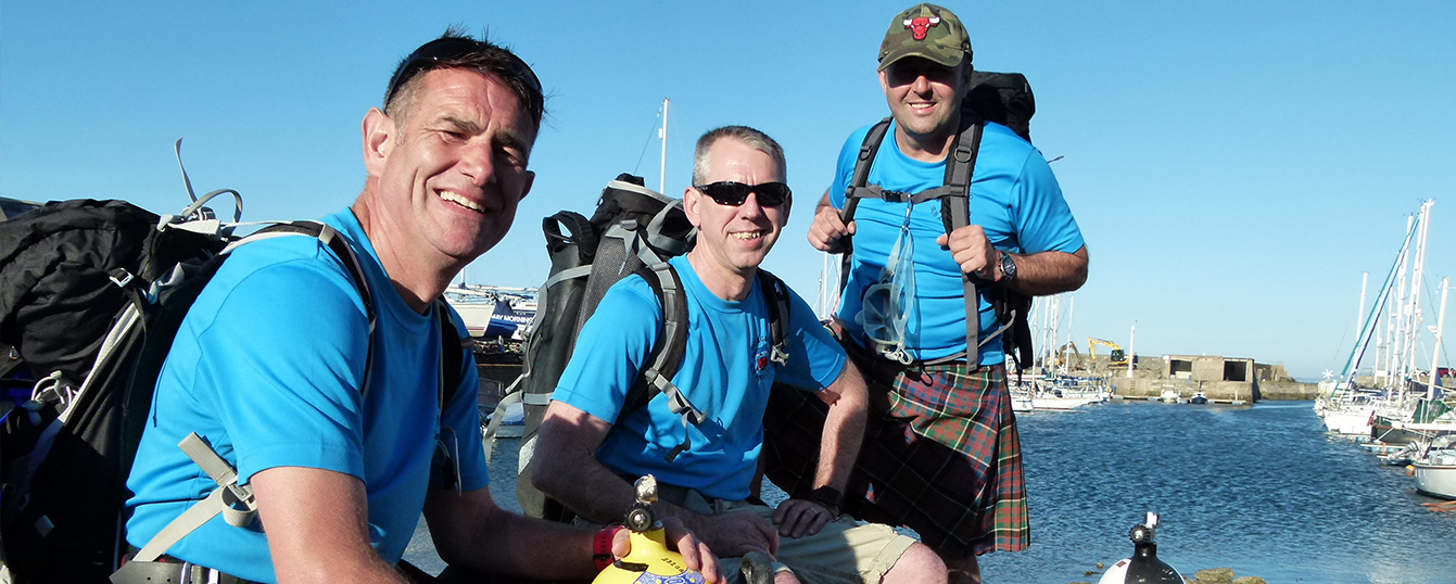 The team from Burghead smile at the camera, laden with dive equipment they are to hike with.